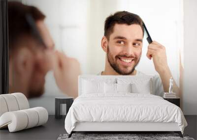 happy man brushing hair with comb at bathroom Wall mural