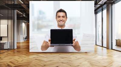 happy man showing laptop blank screen at home Wall mural