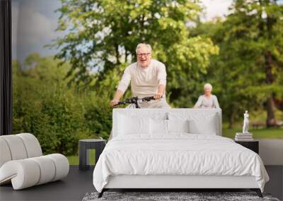 happy senior couple riding bicycles at summer park Wall mural