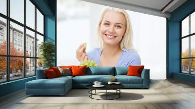 happy woman eating grapes at home Wall mural