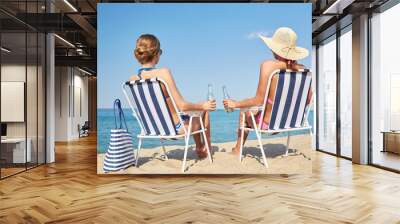 happy women sunbathing in lounges on beach Wall mural