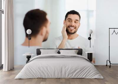 happy young man applying cream to face at bathroom Wall mural