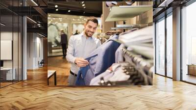 happy young man choosing clothes in clothing store Wall mural