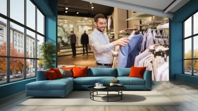 happy young man choosing clothes in clothing store Wall mural