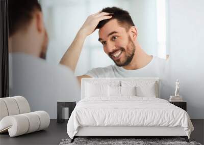 happy young man looking to mirror at home bathroom Wall mural