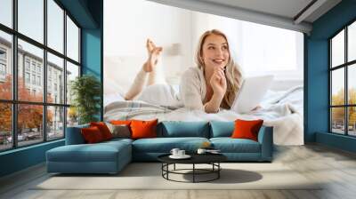 happy young woman with notebook in bed at home Wall mural