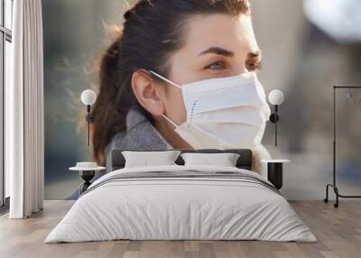 health, safety and pandemic concept - young woman wearing protective medical mask outdoors Wall mural