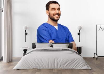 healthcare, profession and medicine concept - happy smiling doctor or male nurse in blue uniform with crossed arms over white background Wall mural