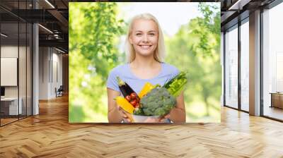 healthy eating, food, dieting and people concept - happy smiling young woman with bowl of vegetables over green natural background Wall mural