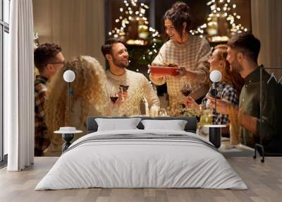 holidays, celebration and people concept - happy smiling friends having christmas dinner at home in evening Wall mural