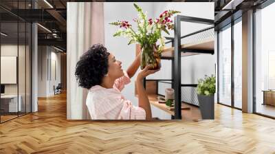 home improvement, decoration and people concept - happy smiling woman placing flowers to shelf Wall mural