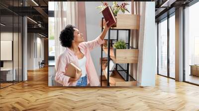 home improvement and people concept - happy smiling woman arranging books on shelving Wall mural