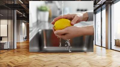 hygiene, health care and safety concept - close up of woman's hands washing lemon fruit in kitchen at home Wall mural