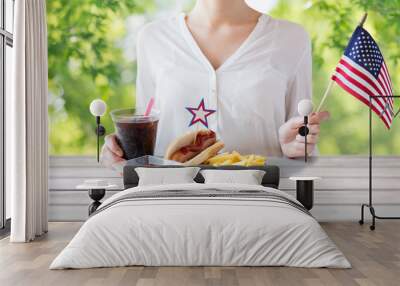 independence day, celebration and holidays concept - close up of woman hands with hot dog and french fries holding american flag and cola drink on 4th july at home party Wall mural