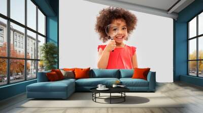 investigation, discovery and vision concept - happy little african american girl looking through magnifying glass over grey background Wall mural