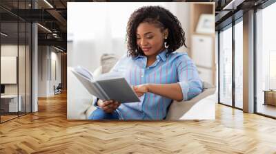 leisure, literature and people concept - smiling african american woman reading book at home Wall mural