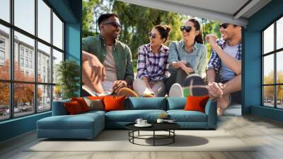 leisure, picnic and people concept - friends hanging out and talking outdoors in summer park Wall mural