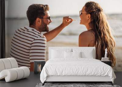 leisure, relationships and people concept - happy couple with food eating and having picnic on beach Wall mural