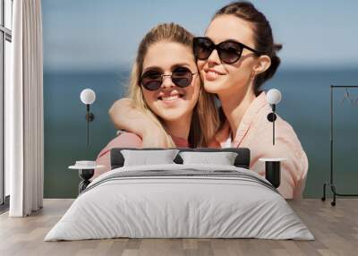 leisure and friendship concept - happy smiling teenage girls or best friends in sunglasses at seaside in summer Wall mural