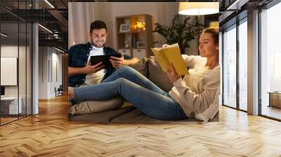 leisure and people concept - happy couple with tablet computer and book at home in evening Wall mural