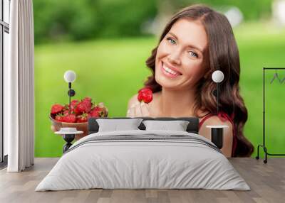 leisure and people concept - portrait of happy woman eating strawberry at summer park Wall mural