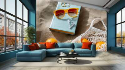 leisure and summer holidays concept - string bag of oranges, earbuds, book and sunglasses on beach sand Wall mural