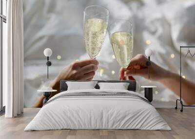 lgbt, same-sex marriage, celebration and love concept - close up of female gay couple hands holding and clinking champagne glasses in bed Wall mural