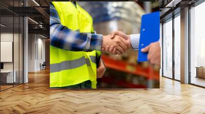 logistic business and cooperation concept - close up of manual worker and businessman with clipboard shaking hands and making deal at warehouse Wall mural