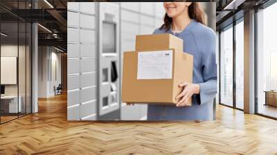 mail delivery and post service concept - close up of happy smiling woman with boxes at outdoor automated parcel machine Wall mural