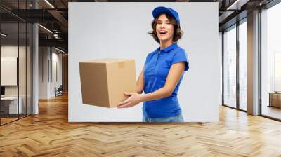 mail service and shipment concept - happy smiling delivery girl with parcel box in blue uniform over grey background Wall mural