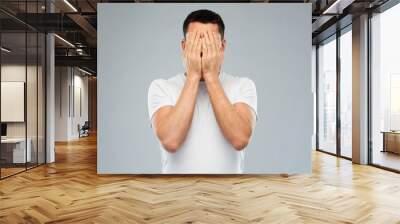 man in white t-shirt covering his face with hands Wall mural