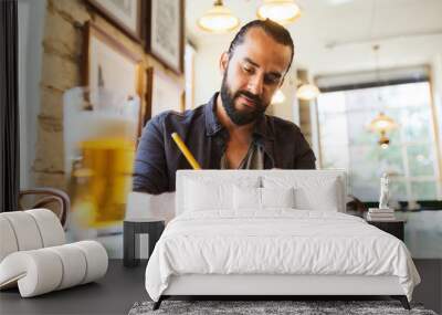 man with beer writing to notebook at bar or pub Wall mural