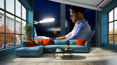 man with laptop and coffee working at night office Wall mural