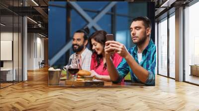 man with smartphone and friends at restaurant Wall mural