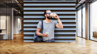 man with smartphone drinking coffee on city street Wall mural