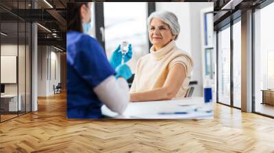 medicine, health and vaccination concept - doctor or nurse filling syringe with vaccine or drug and senior woman at hospital Wall mural