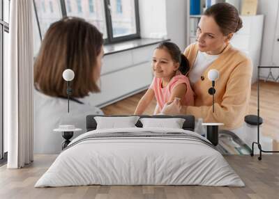 medicine, healthcare and pediatry concept - female doctor or pediatrician disinfecting arm skin of little girl patient with mother at clinic Wall mural