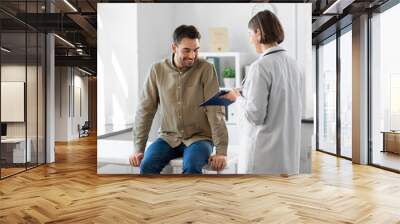 medicine, healthcare and people concept - female doctor with clipboard and happy smiling man patient meeting at hospital Wall mural