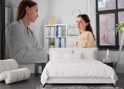 medicine, healthcare and people concept - female doctor with clipboard talking to smiling woman patient at hospital Wall mural