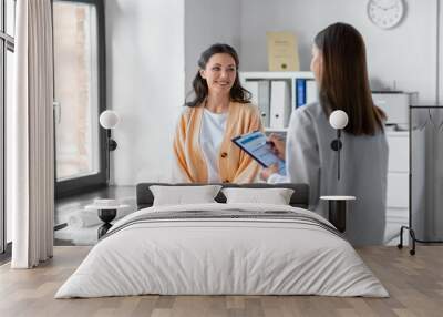 medicine, healthcare and people concept - female doctor with clipboard talking to smiling woman patient at hospital Wall mural