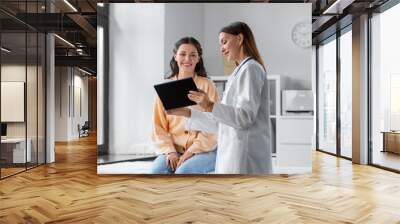 medicine, healthcare and people concept - female doctor with tablet pc computer talking to smiling woman patient at hospital Wall mural