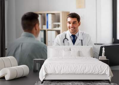 medicine, healthcare and people concept - smiling doctor talking to male patient at medical office in hospital Wall mural