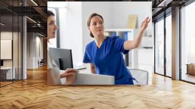 medicine, people and healthcare concept - female doctor or nurse showing something to patient at hospital Wall mural