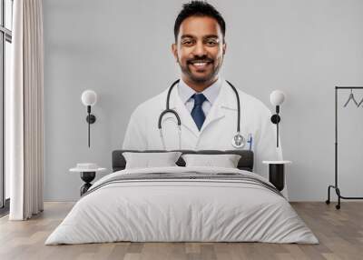 medicine, profession and healthcare concept - smiling indian male doctor in white coat with stethoscope over grey background Wall mural