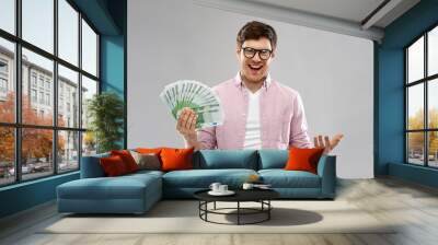 money, finance, business and people concept - happy young man in glasses with fan of one hundred euro bank notes over grey background Wall mural