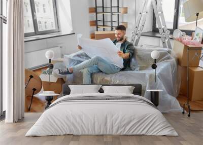 moving, people and real estate concept - happy smiling man with blueprint and boxes at new home Wall mural