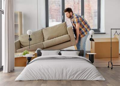 moving, people and real estate concept - man dragging sofa at new home Wall mural