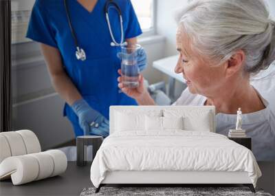 nurse giving medicine to senior woman at hospital Wall mural