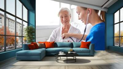 nurse with stethoscope and senior woman at clinic Wall mural