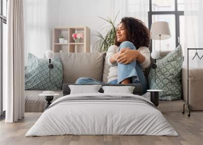 people, race, ethnicity and portrait concept - happy african american young woman sitting on sofa at home Wall mural